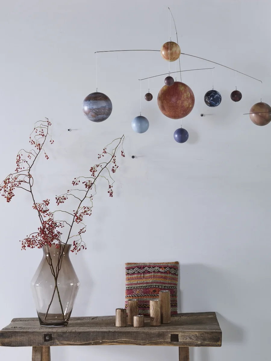 Mobile du système solaire suspendu au-dessus d’une console avec un vase de branches