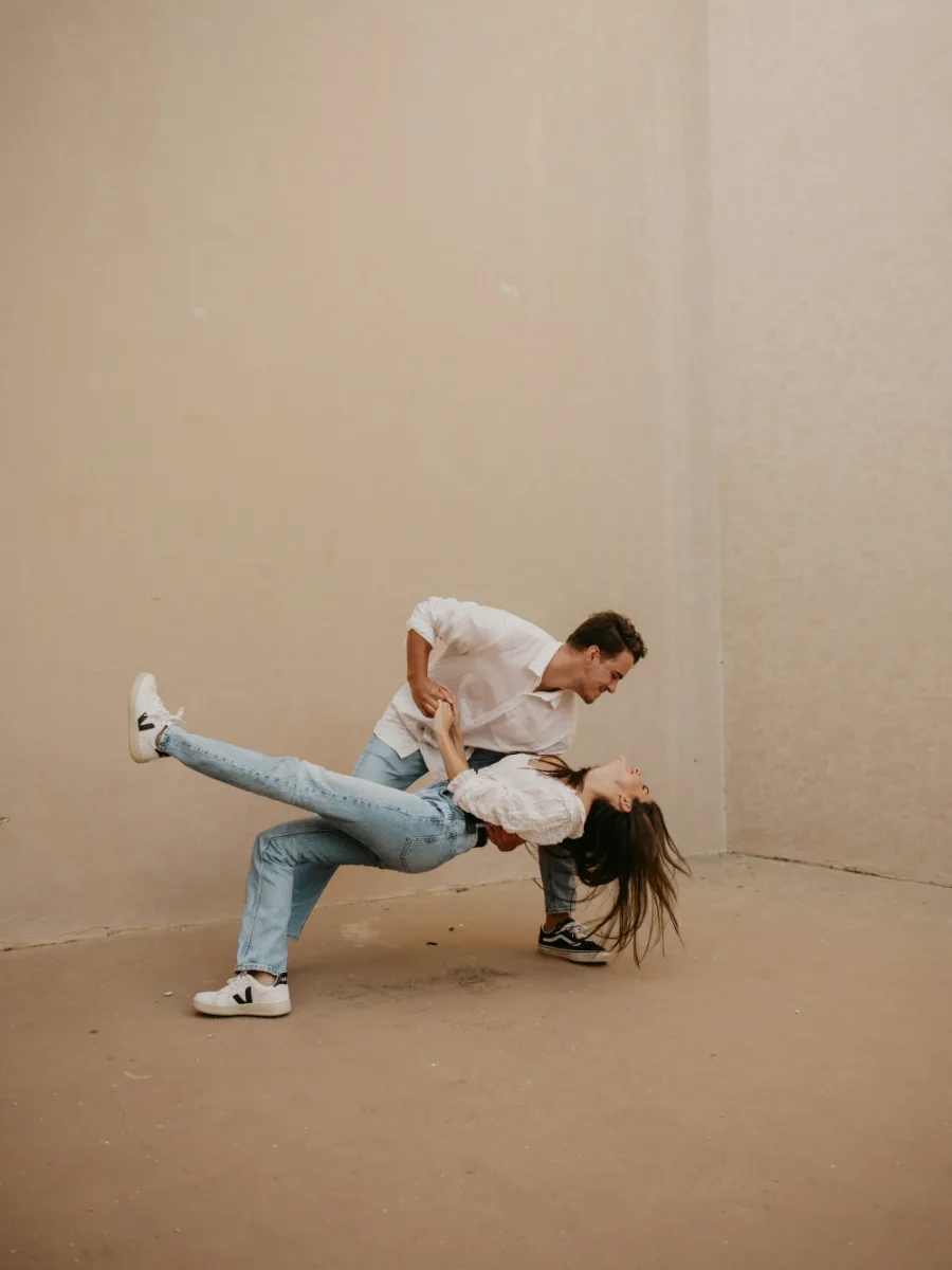 Un couple qui danse, elle en appui sur sa jambe à lui, sur fond beige
