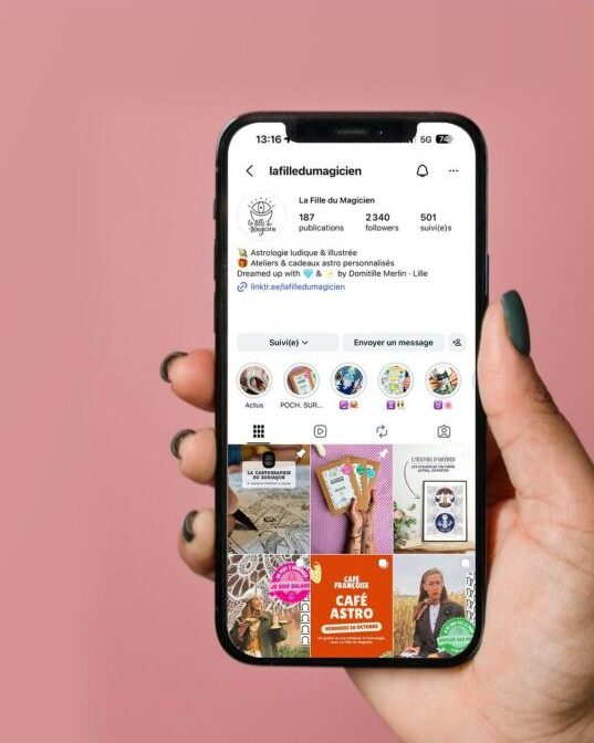 Main tenant un téléphone affichant le compte Instagram de La Fille du Magicien