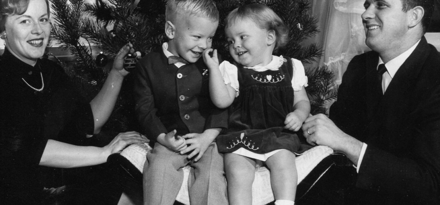 Photo de famille des années 1960 : deux enfants éclatent de rire entre leurs parents